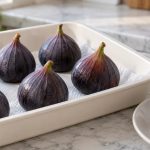 Figues fraîches espacées dans un contenant peu profond, avec une figue ouverte à côté.